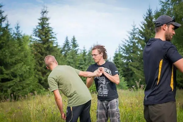 Zwei Personen üben eine Technik zur Selbstverteidigung in einer Wiese