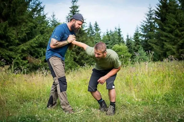 Zwei Personen üben eine Technik zur Unterstützung in einem Grasfeld aus