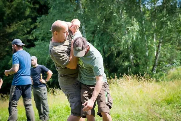 Zwei Personen üben einen Nahkampfgriff auf einer Wiese