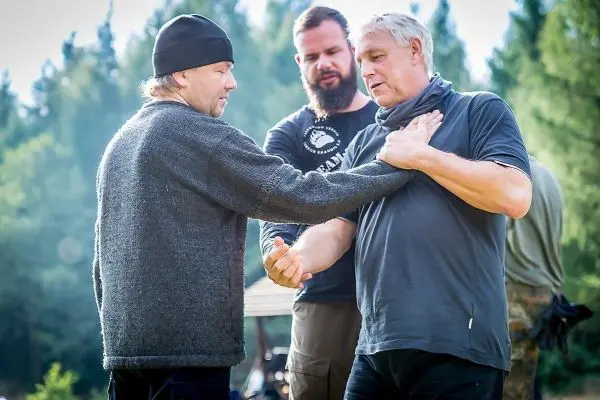 Drei Männer üben eine Technik zur Selbstverteidigung im Freien