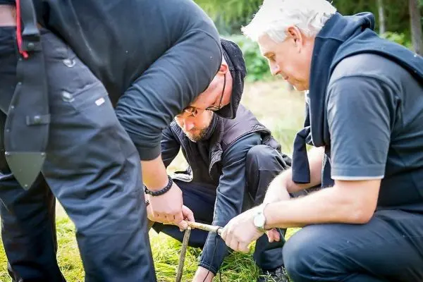 Drei Personen arbeiten gemeinsam an einer Holzstruktur auf dem Boden