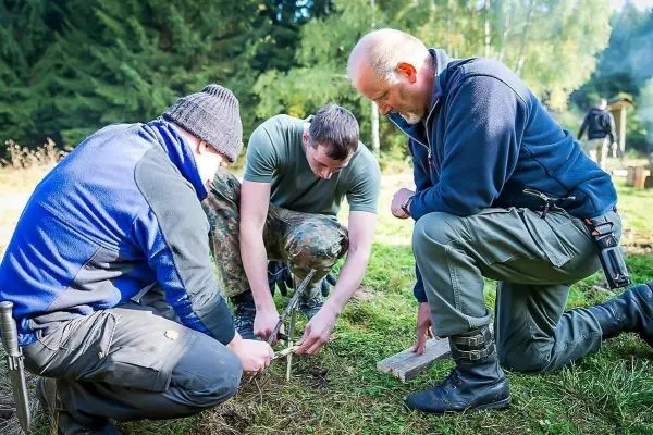Drei Personen arbeiten gemeinsam an einer Holzstruktur im Freien