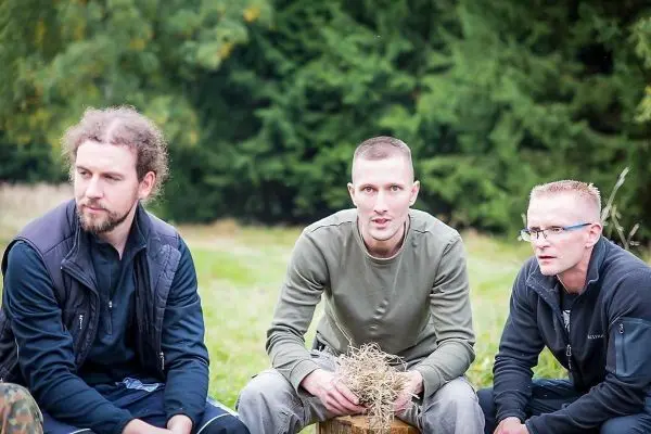 Drei Personen sitzen im Freien und halten Zunder in den Händen