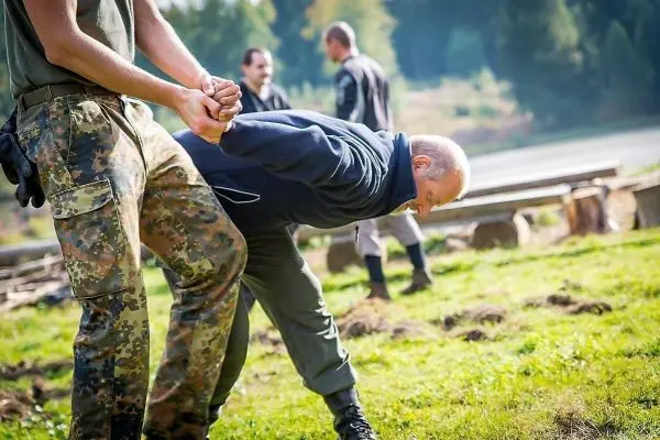 Ein Mann wird von einer Person in militärischer Kleidung festgehalten