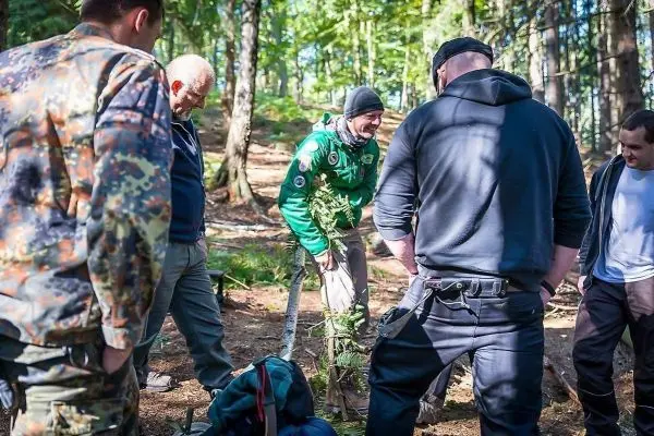Gruppe von Personen betrachtet eine selbstgebaute Konstruktion im Wald