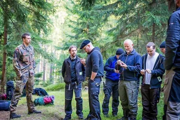 Gruppe von Personen steht im Wald und betrachtet Geräte oder Ausrüstung