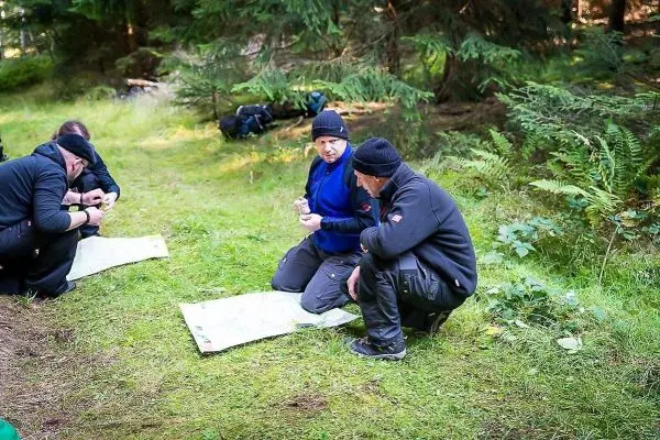 Gruppendiskussion über Karten und Orientierung im Wald auf grüner Wiese