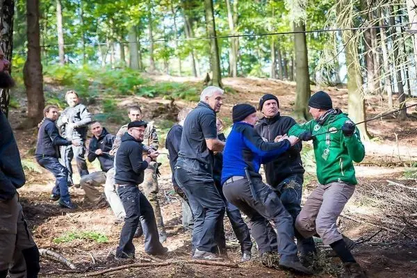 Gruppendynamik während einer Seilquerung im Wald, Teilnehmer ziehen an einem Seil