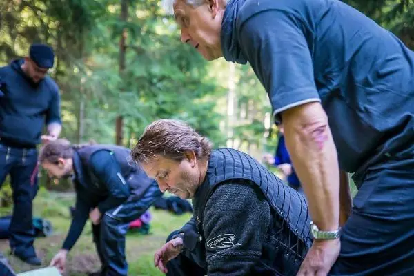 Gruppenteilnehmer arbeiten am Boden, während einer über die Schulter schaut