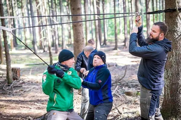 Gruppierung arbeitet an einer selbstgebauten Seilbrücke zwischen zwei Bäumen