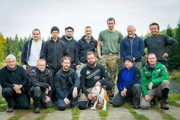 Gruppierung von Personen in Outdoor-Bekleidung, einige knien, andere stehen