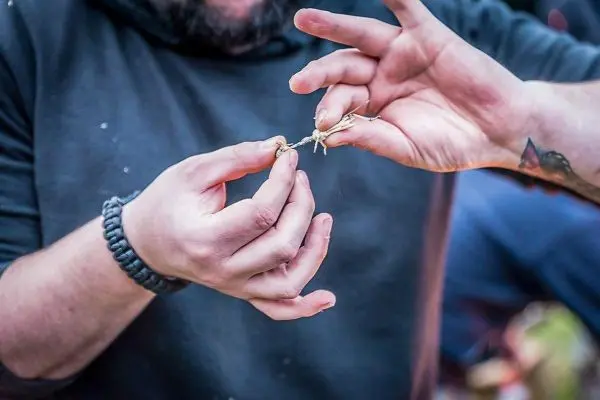 Hände binden Zunder mit einer Schnur zusammen