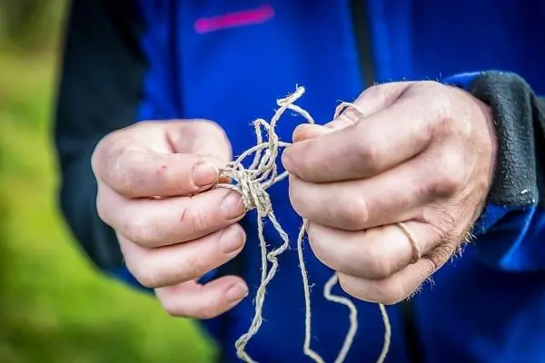 Hände halten mehrere Stränge Schnur, die miteinander verknotet sind
