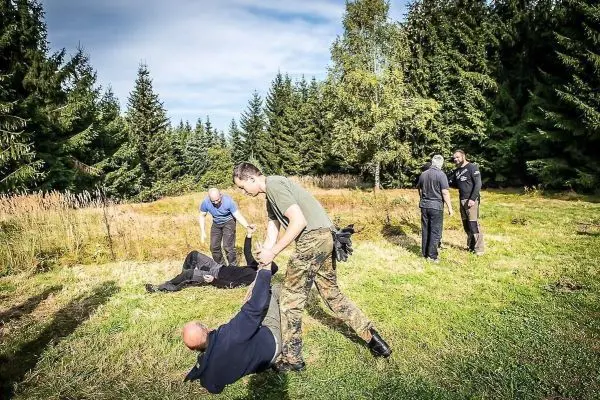 Kämpfer zieht einen am Boden liegenden Mann in einer Waldlichtung