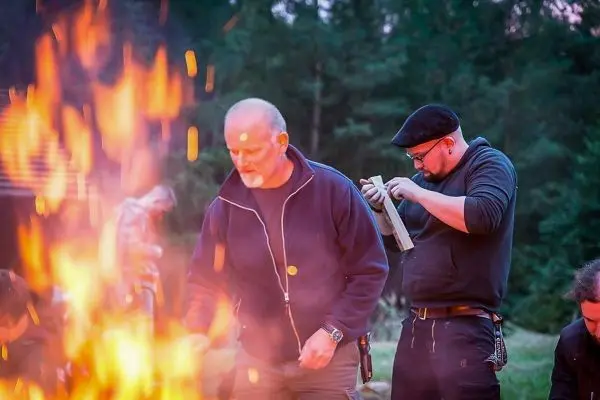 Kleines Bodenfeuer brennt vor zwei Personen, eine bereitet etwas vor