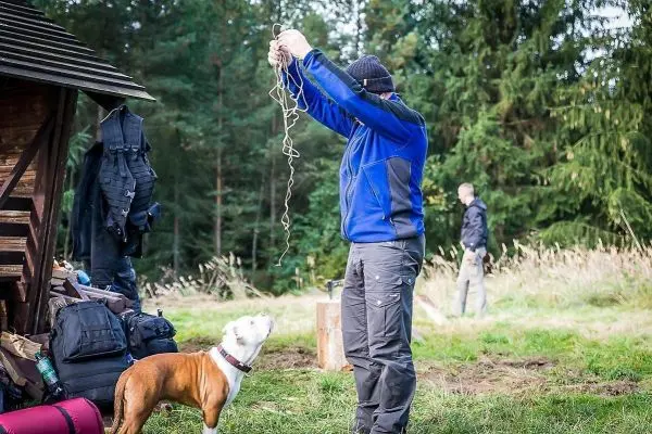 Mann hält ein Seil über Kopf, Hund steht davor und schaut auf ihn