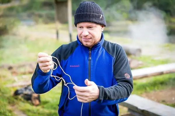 Mann hält ein Stück Schnur in der Hand und betrachtet es aufmerksam