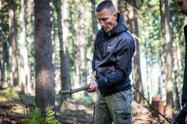 Mann hält einen Stock in einem Waldgebiet