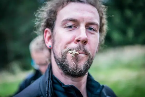 Mann mit einem Insekt im Mund und Bart, Hintergrund unscharf