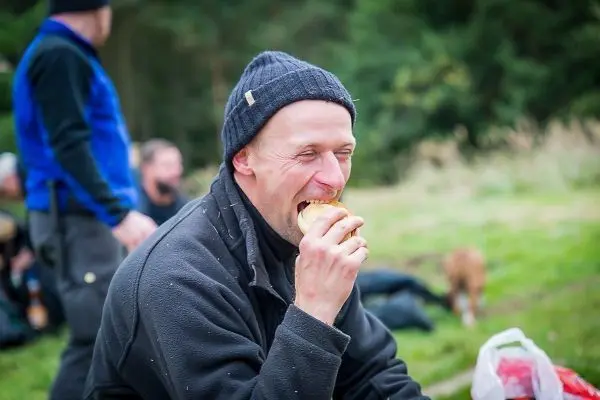 Mann sitzt im Freien und beißt in ein Sandwich