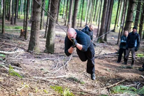 Mann überquert selbstgebaute Seilbrücke im Wald