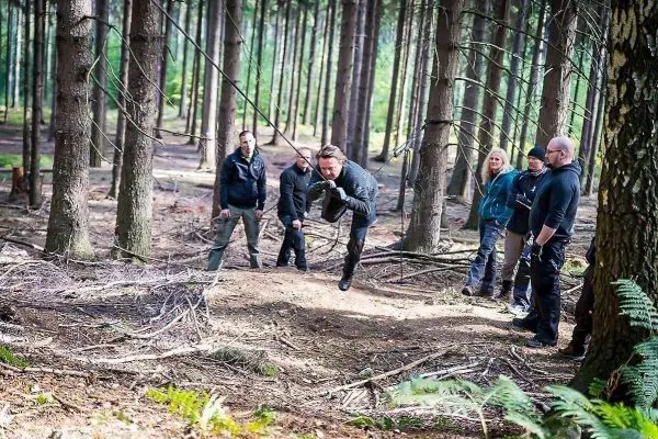 Mann überquert selbstgebaute Seilbrücke, während andere zuschauen