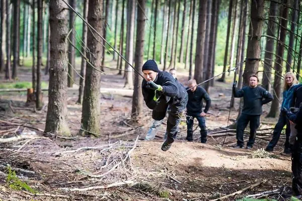 Mann überquert selbstgebaute Seilbrücke zwischen Bäumen im Wald