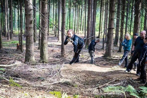 Mann überquert selbstgebaute Seilbrücke zwischen Bäumen im Wald
