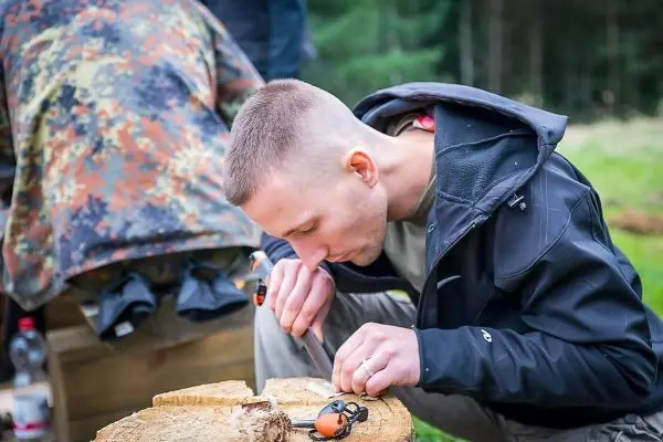 Messer bearbeitet Holzstück auf einem Baumstamm