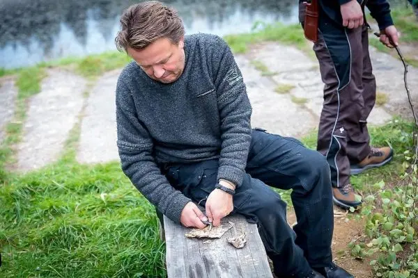 Messer bearbeitet Holzstück auf einer Bank am Wasser