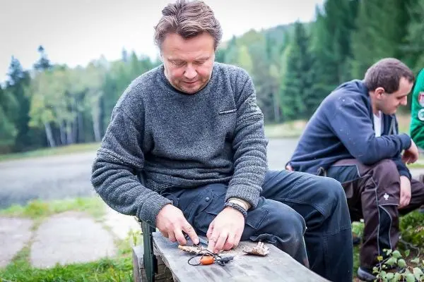 Messer schneidet Holzstücke auf einer Holzbank am Ufer eines Gewässers