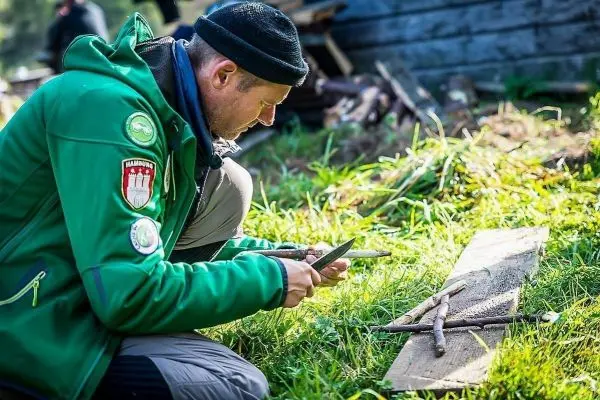 Messer schneidet Holzstücke auf einer Holzplatte im Gras