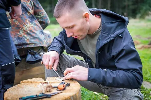 Messer schnitzt Holzstück auf einem Baumstumpf im Freien