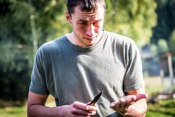 Messer wird auf die Handfläche gerichtet, während konzentriert geschaut wird