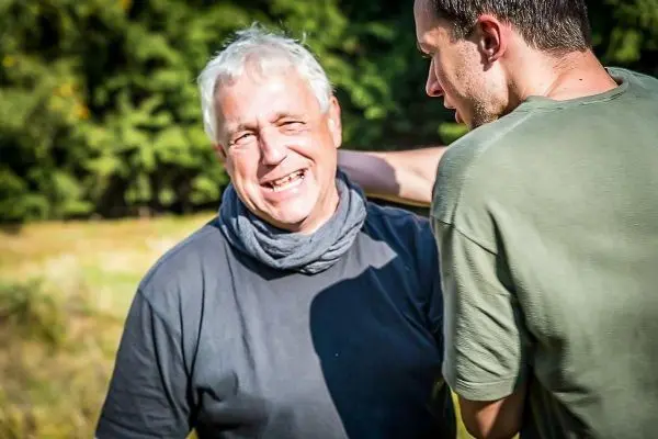 Person lächelt und steht neben einer anderen Person im Freien