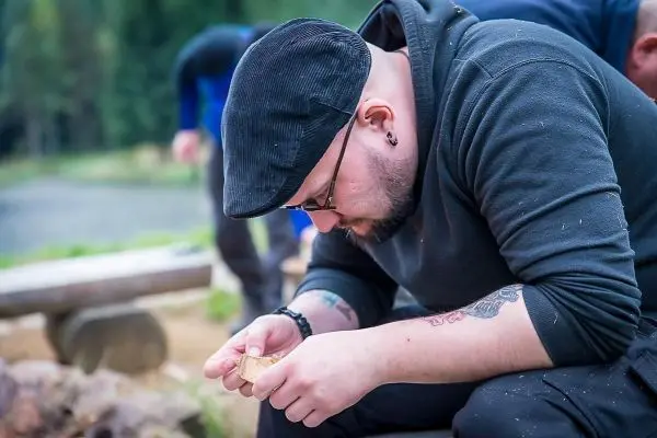 Person schnitzt mit einem Messer in der Hand