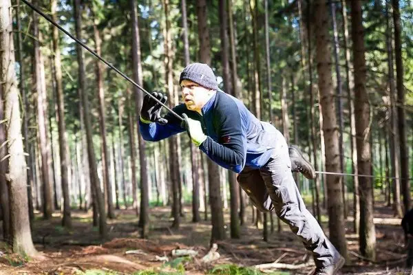 Person schwingt an einem Seil zwischen Bäumen