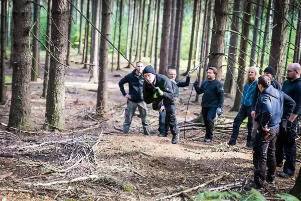Person springt von einer selbstgebauten Seilbrücke, Gruppe beobachtet
