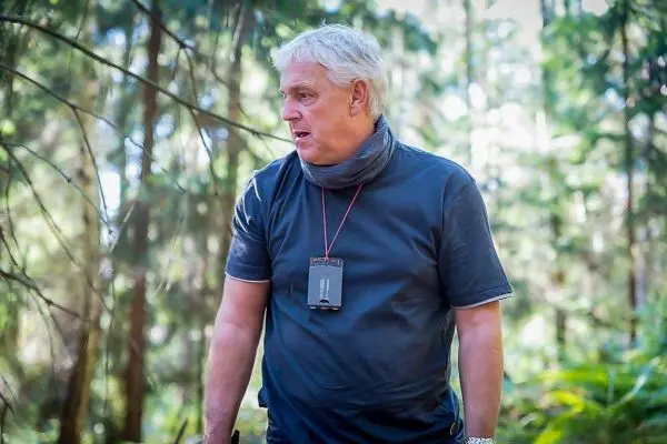 Person steht im Wald, trägt ein schwarzes T-Shirt und einen Schal