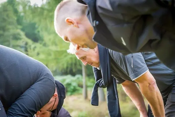 Personen beugen sich über den Boden beim Üben im Outdoorkurs