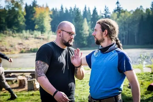 Zwei Männer stehen sich gegenüber und führen eine Diskussion am Ufer eines Gewässers