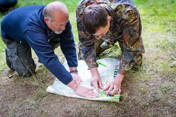 Zwei Personen analysieren eine Karte auf dem Boden