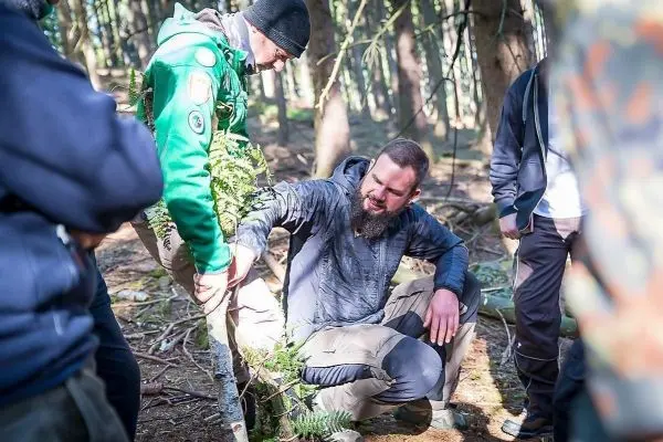 Zwei Personen arbeiten an einer selbstgebauten Konstruktion aus Ästen im Wald