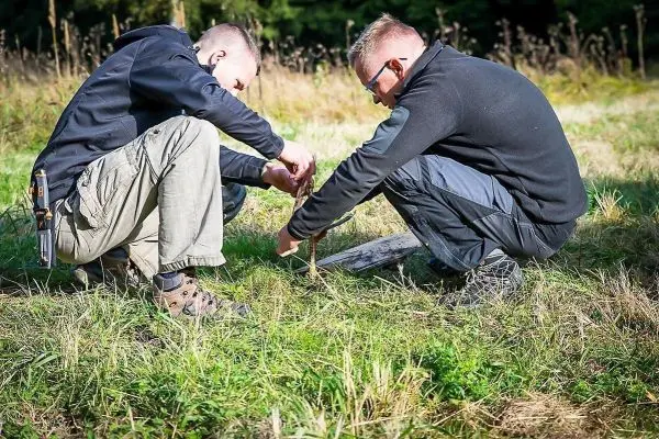 Zwei Personen bauen eine Feuerstelle im Gras auf