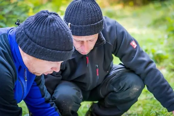 Zwei Personen beugen sich über den Boden und untersuchen etwas