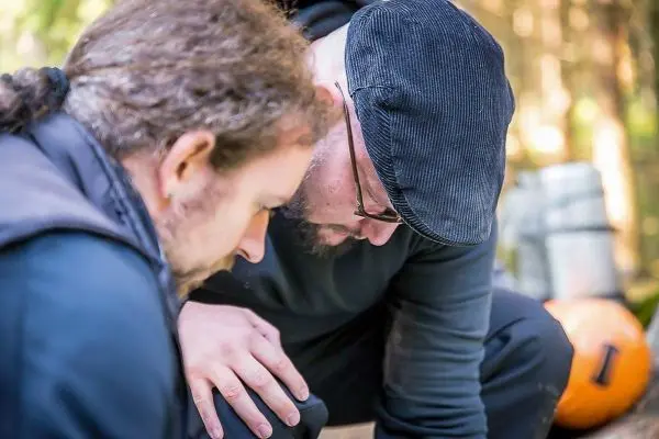 Zwei Personen beugen sich über einen Gegenstand im Freien