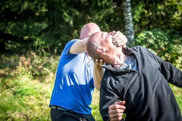 Zwei Personen führen eine Selbstverteidigungstechnik im Freien aus