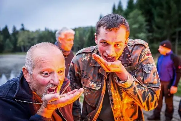 Zwei Personen halten ihre Hände mit Nahrung vor den Mund, im Hintergrund eine Gruppe