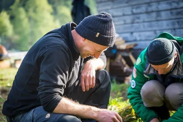 Zwei Personen knien am Boden und betrachten etwas im Gras