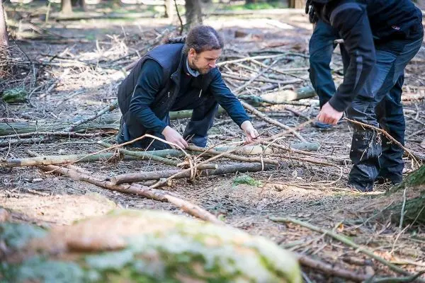 Zwei Personen sammeln Äste und Zweige im Wald für eine Konstruktion